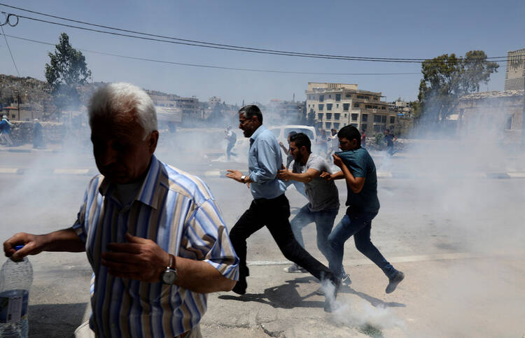 Palestinian protesters run for cover from tear gas fired by Israeli troops in clashes on May 15 during a protest in the West Bank town of Bethlehem marking the 69th anniversary of their uprooting. Palestinians call the 1948 uprooting "nakba" or catastrophe. (CNS photo/Ammar Awad, Reuters)