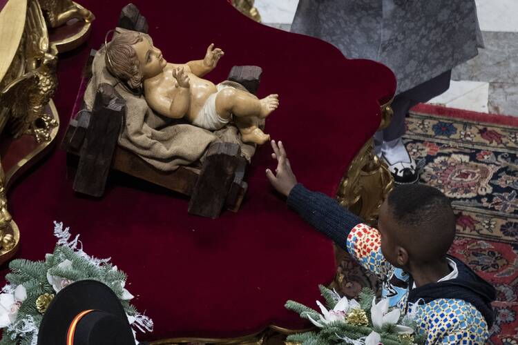 A child touches a figurine of the baby Jesus as Pope Francis celebrates Christmas Eve Mass in St. Peter's Basilica at the Vatican Dec. 24, 2022. (CNS photo/Cristian Gennari, pool)