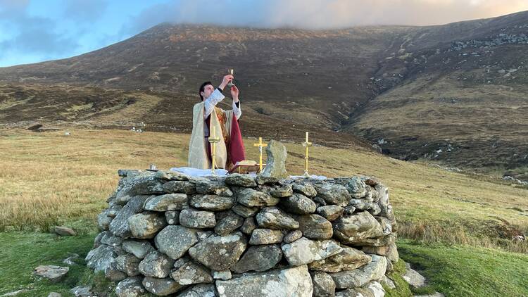 Father Gerard Quirke raises the chalice at Mass Rock overlooking Keem Bay on Ireland's Achill Island April 4, 2021. The church in Ireland is launching a Year for Vocations as it grapples with a steep decline in seminary numbers and with aging priests. (OSV News photo/Seán Molloy, courtesy Irish Catholic)