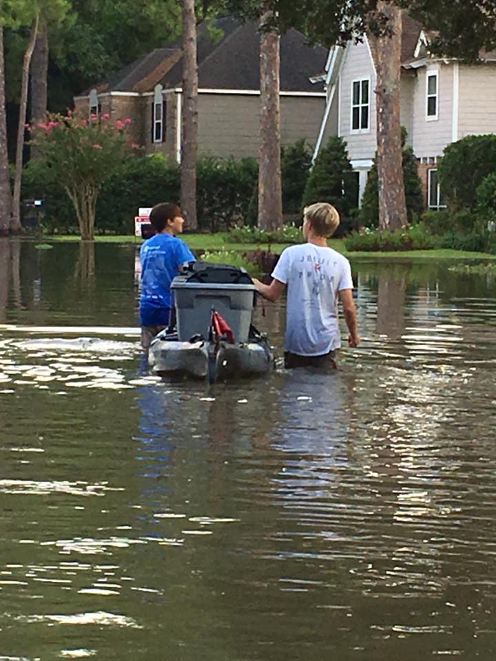 Two Strake Jesuit students guide a kayak full of belongings through Hurricane Harvey floodwaters. (Photo by Sharon Lundrigen)