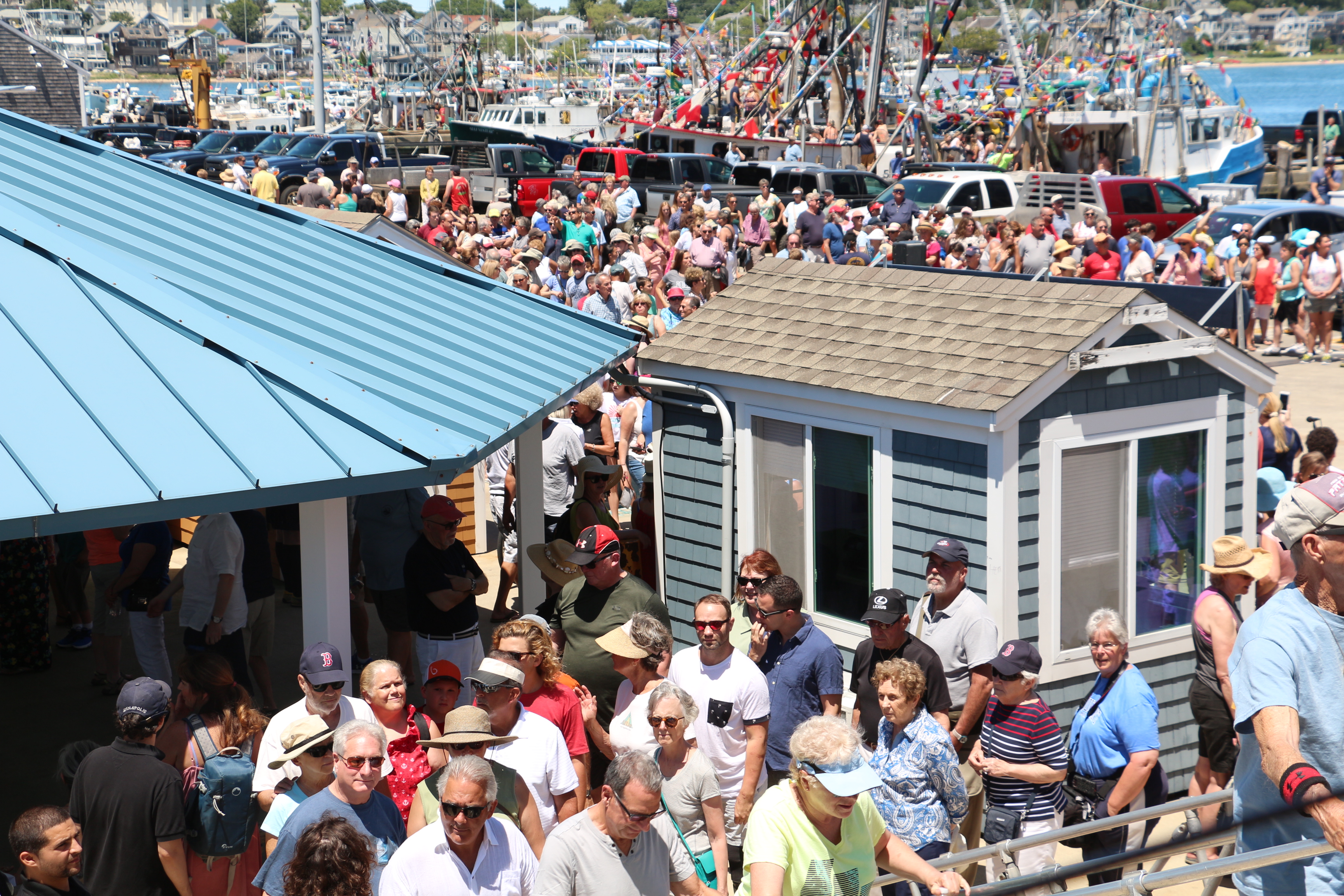 Crowds line up to board the ferry on which the bishop will stand to bless the fishing fleet.