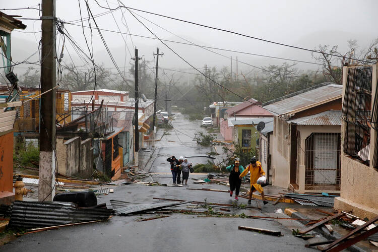 Rescue workers help people on Sept. 20 in Guayama, Puerto Rico, after the area was hit by Hurricane Maria. After battering the Virgin Islands, the hurricane made landfall in Puerto Rico, bringing "catastrophic" 155 mph winds and dangerous storm surges. (CNS photo/Carlos Garcia Rawlins, Reuters)