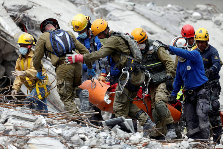 Members of Israeli and Mexican rescue teams carry a body from a collapsed building in Mexico City on Sept. 21, two days after an earthquake. (CNS photo/Carlos Jasso, Reuters)