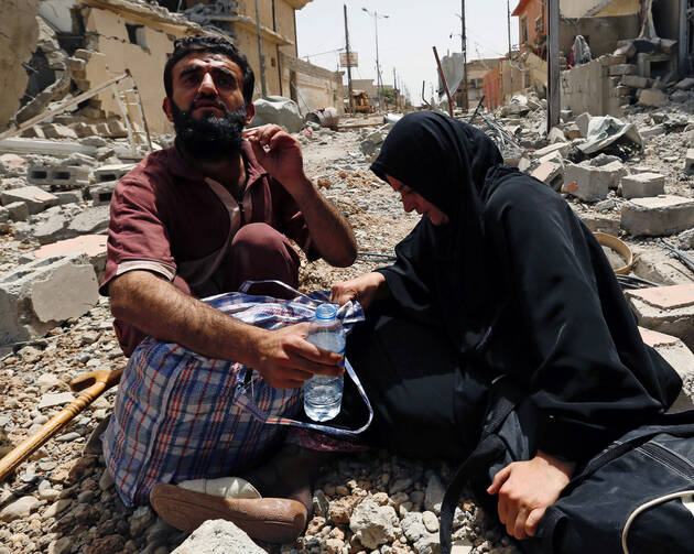 Displaced Iraqis rest amid rubble after fleeing fighting between Iraqi Counter Terrorism Service forces and Islamic State militants May 15 in Mosul. (CNS photo/Danish Siddiqui, Reuters)